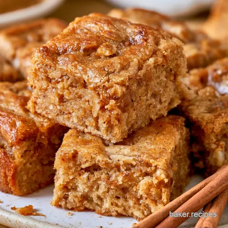 Two square dessert bars stacked on a white marble plate, garnished with a cinnamon stick and a whole star anise.